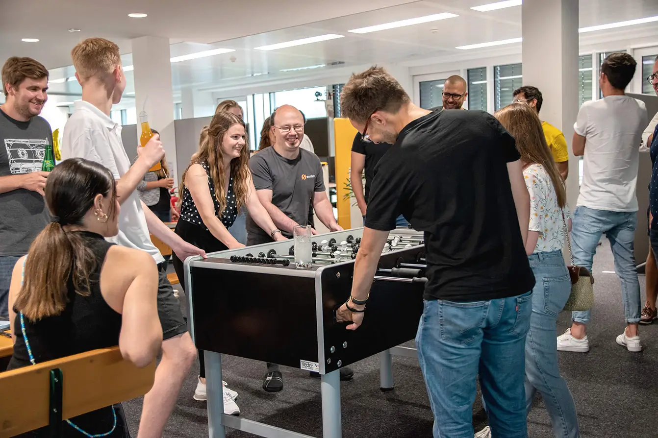 Mitarbeiter*innen von Sunlab spielen Tischkicker beim Sommerfest